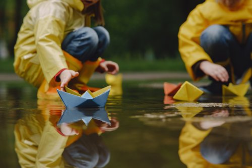 Kinder lassen Papierboote ins Wasser