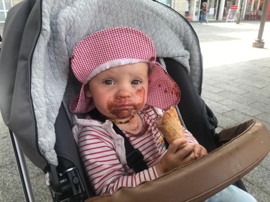 Ein Kind im Kinderwagen isst ein Eis
