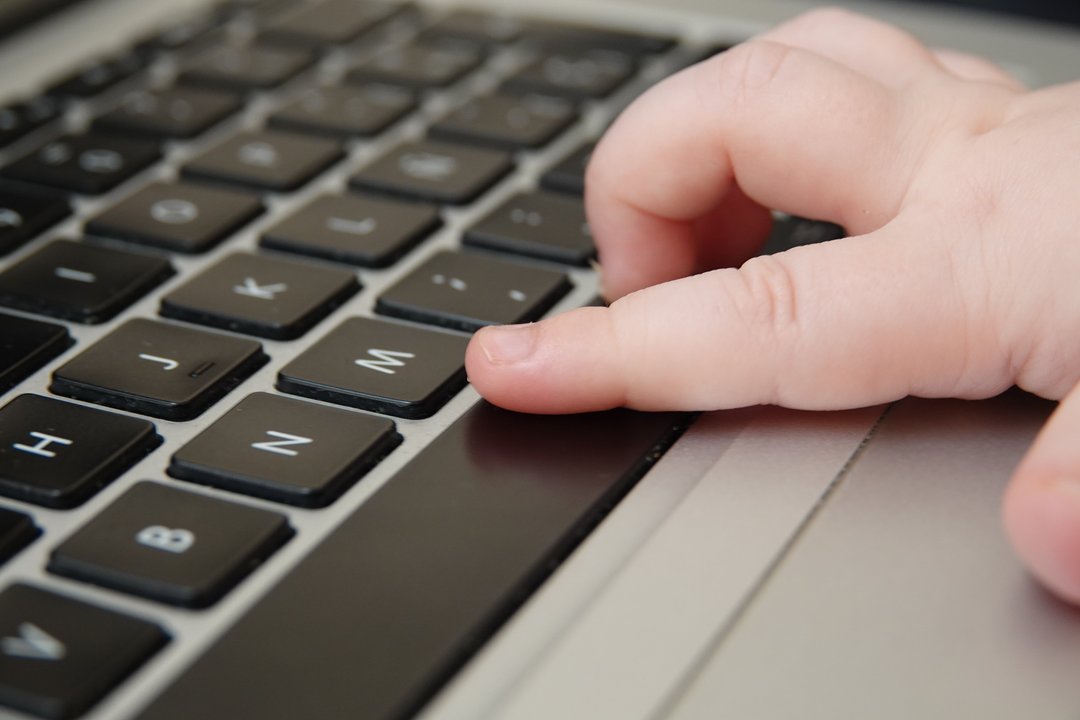 Der Zeigefinger eines Babys auf der Tastatur des Laptops - im Begriff, die Leertaste zu drücken